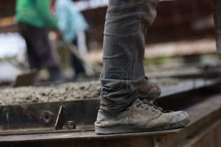 Nahaufnahme von Fuß und Schuhen von Arbeitern oder Arbeitern auf der Baustelle