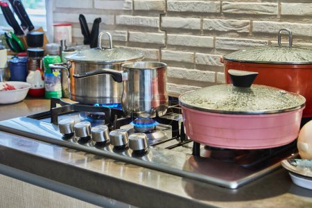 Téléchargez les photos : Cooking food in frying pan and pot on gas stove in the kitchen. Home cooking concept. - en image libre de droit