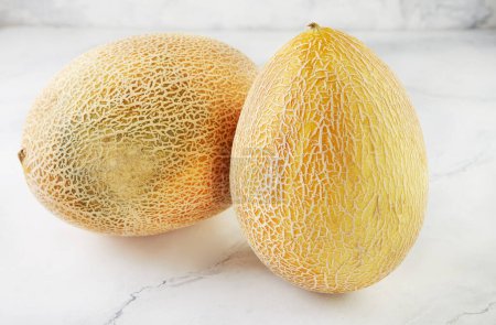 Photo for Two melons on light marble in home kitchen. - Royalty Free Image