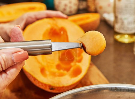 Téléchargez les photos : Chef coupe des boules de melon avec cuillère spéciale dans la cuisine. - en image libre de droit