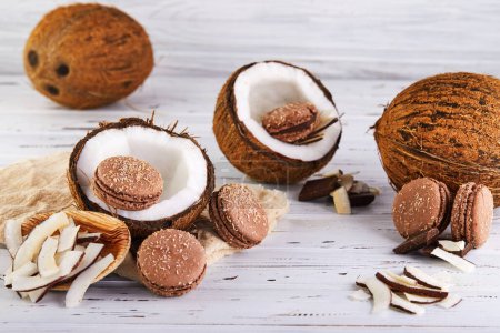 Macarrones de coco con hojuelas de chocolate y coco en una mesa con un coco en el fondo. La imagen perfecta para un blog de alimentos o sitio web de recetas.