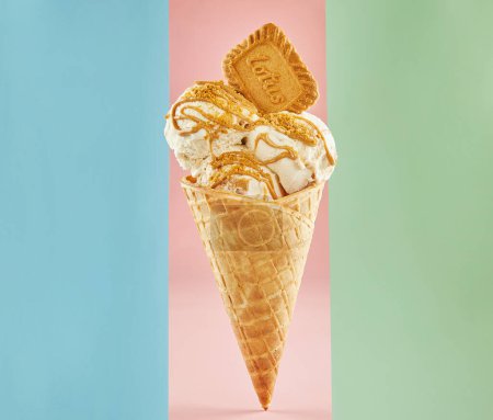 Delicious ice cream cone with a crispy biscuit on a colorful background. Generously topped with luscious caramel sauce for extra sweetness. Perfect for food-related content.
