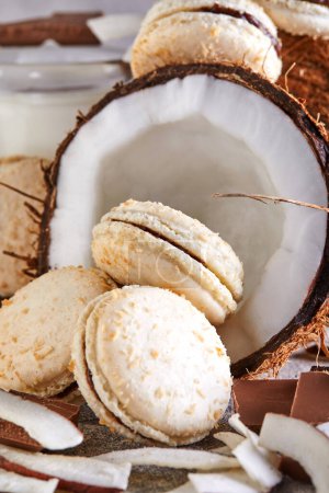 Kokos-Macarons mit Schokolade und Kokosflocken auf einem Tisch mit einer Kokosnuss im Hintergrund. Das perfekte Image für einen Food-Blog oder eine Rezept-Website.