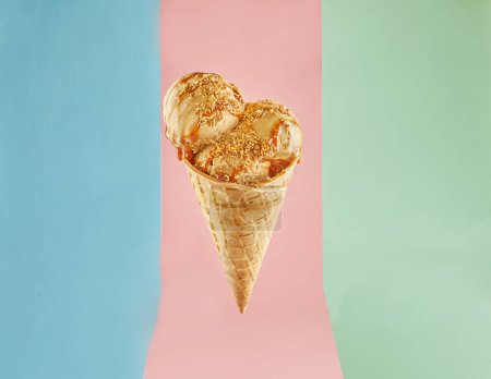 Golden-coated ice cream cone with three creamy scoops against a vibrant background. The scoops are in flavors of blue, pink, and green. Topped with crunchy nuts for an indulgent treat.