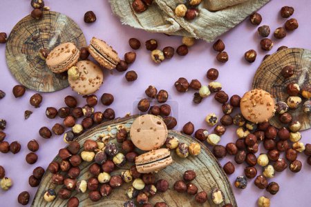 Delicious hazelnut flavored macarons beautifully arranged on a purple background on a wooden stand. Ideal image for pastries, desserts or food blog content. Flat lay