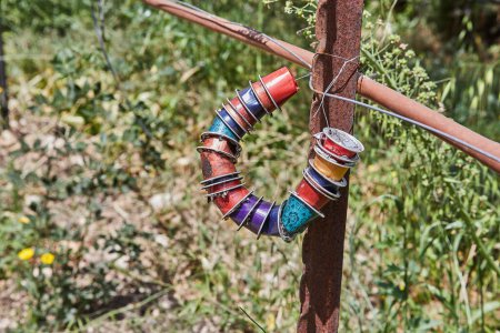 A horseshoe crafted from Nespresso capsules is hanging as decor on a fence post, showcasing creativity and art using unconventional materials