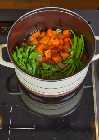 Pot avec ingrédients pour soupe à la crème sur une cuisinière électrique.
