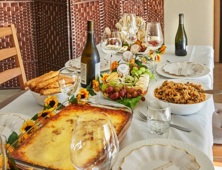 Eine elegante Schawuot-Festtafel mit Wein, Käse, Obst und Weihnachtsdekorationen, bereit für ein traditionelles jüdisches Festmahl. Glückliche Shavuot-Inschriften auf Hebräisch.