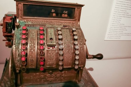 Vintage metal cash register with round buttons with numbers in a sepia tone