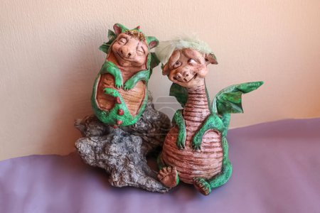 Zwei handgefertigte Puppen von grünen Mamas und Baby-Familiendrachen mit Flügeln auf pfirsichfarbenem Hintergrund