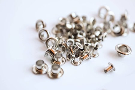 Photo for Metal silver eyelets on white table with bokeh blur in bright day light side view - Royalty Free Image