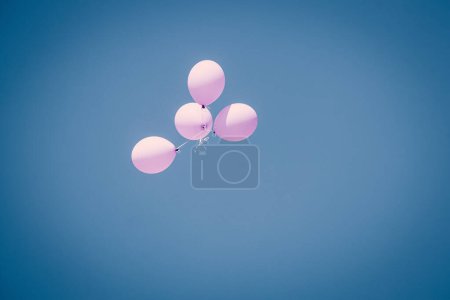 Hellrosa Luftballons in blauem Sommersonnenhimmel, die auf blauem Himmelshintergrund auf- und abfliegen