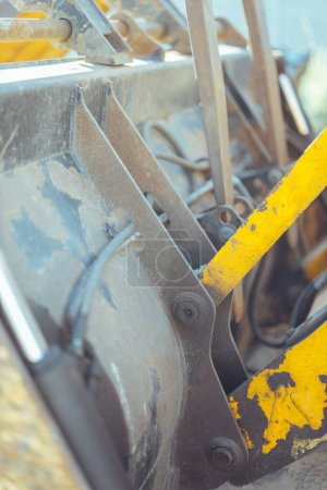 Photo for Close-up of a yellow tractor with a big dirty bucket on a construction site in bright sunlight. front view - Royalty Free Image