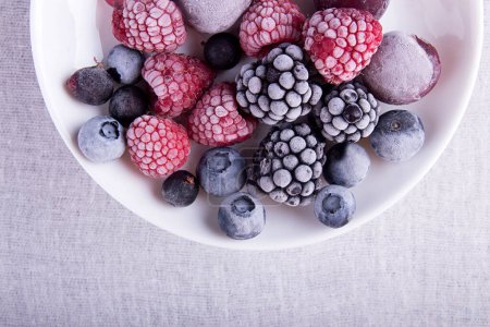 Photo for Frozen raspberries, blackberries, blueberries, blueberries, cherries, black currants on a white plate on a white background. - Royalty Free Image