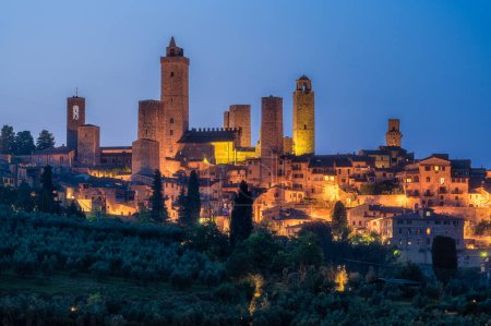 Foto de La maravillosa ciudad de San Giminiano con todas sus torres iluminadas en una tarde de verano. Provincia de Siena, Toscana, Italia. - Imagen libre de derechos