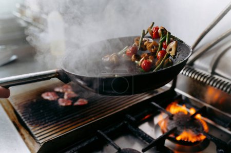 Téléchargez les photos : Cooking vegetables in a pan on a gas stove. tomatoes, champignons, mushrooms, beans. - en image libre de droit