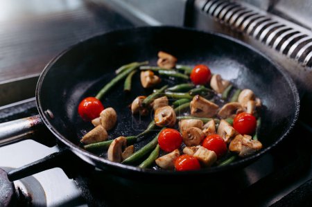 Téléchargez les photos : Cooking vegetables in a pan on a gas stove. tomatoes, champignons, mushrooms, beans. - en image libre de droit