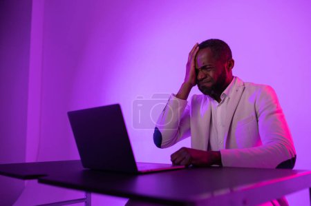 Foto de Angry man at work. angry african american worker looking at laptop screen with software problems. computer error - Imagen libre de derechos