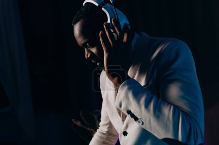 Foto de Portrait of a smiling man in headphones. Listening to music. a man in a white jacket and trousers. - Imagen libre de derechos
