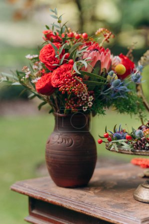 Téléchargez les photos : Cruche en argile avec des fleurs sur une table en bois. - en image libre de droit