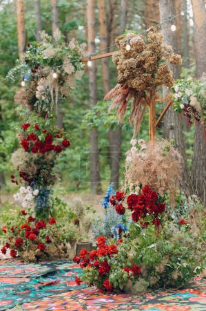 Foto de A beautiful arch with intertwined fresh flowers at a wedding ceremony in a green park. - Imagen libre de derechos