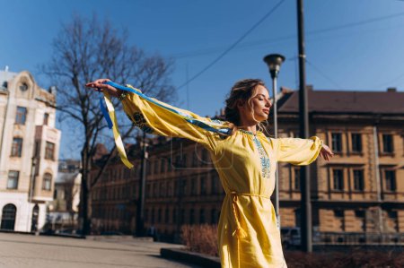 Téléchargez les photos : Une fille dans une robe jaune ukrainienne marche dans la rue par une journée ensoleillée - en image libre de droit
