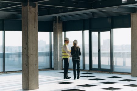 Foto de Dos ingenieros de arquitectos están caminando en un edificio de oficinas construido. - Imagen libre de derechos