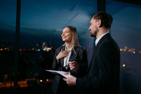 Foto de Oficinistas hombres y mujeres hablando. Socios de negocios hablando en la oficina nocturna - Imagen libre de derechos