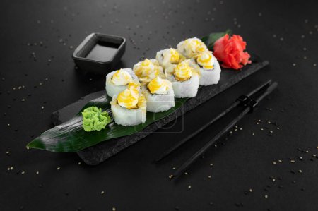Téléchargez les photos : Rouleau de sushi avec fromage à la crème, riz, sauce. Maki sushi roule sur un fond noir. - en image libre de droit