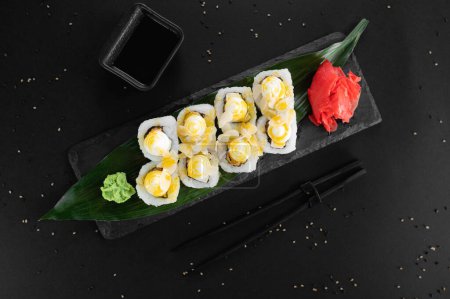Téléchargez les photos : Rouleau de sushi avec fromage à la crème, riz, sauce. Maki sushi roule sur un fond noir. - en image libre de droit