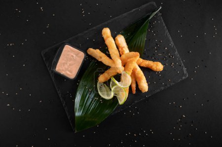Foto de Camarones fritos. Camarones fritos dispuestos en un plato de piedra negra con salsa - Imagen libre de derechos