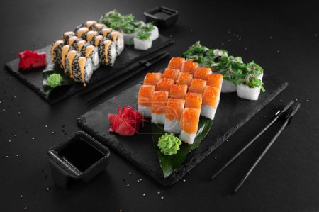 Foto de Un conjunto de sushi y rollos con pescado. Un conjunto de papeles sobre un fondo negro. - Imagen libre de derechos