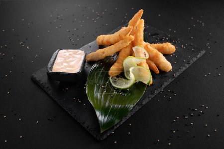 Téléchargez les photos : Crevettes frites. Crevettes frites disposées sur une assiette en pierre noire avec sauce - en image libre de droit