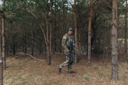 Photo for A soldier walks through the forest with a machine gun. - Royalty Free Image