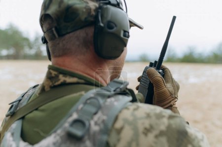 a soldier talks on a walkie-talkie.