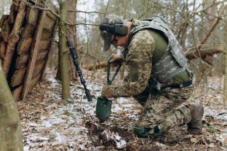 Téléchargez les photos : Un soldat avec une pelle à la main creuse le sol. - en image libre de droit