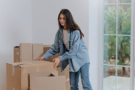 Foto de Una mujer empaca sus pertenencias en cajas para mudarse a un nuevo apartamento. mudarse a una casa. - Imagen libre de derechos