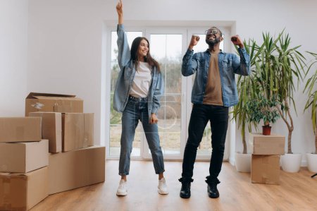 Photo for Young happy couple in room with moving boxes at new home - Royalty Free Image