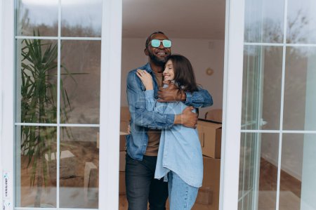 Téléchargez les photos : Joyeux jeune homme embrassant femme excitée célébrant jour de déménagement avec des boîtes en carton, locataires - en image libre de droit