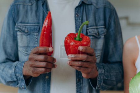 Photo for Dark-skinned man holding red sweet pepper. Close-up of red pepper in hands. - Royalty Free Image