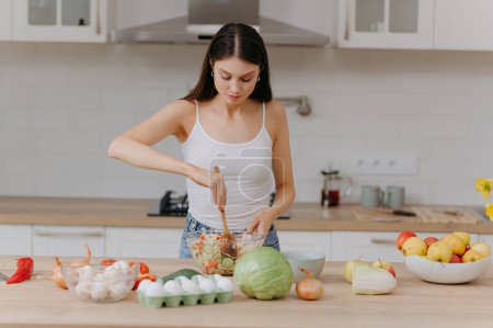 Téléchargez les photos : Femme avec salade à table en bois dans la cuisine, gros plan. Régime alimentaire Keto - en image libre de droit
