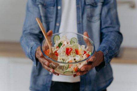Photo for An African-American man prepares a vegetable salad, a healthy meal. - Royalty Free Image