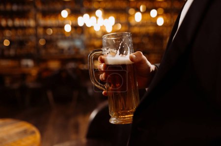 Foto de Un hombre bebe cerveza. Vista lateral del hombre calvo guapo bebiendo cerveza en el pub - Imagen libre de derechos