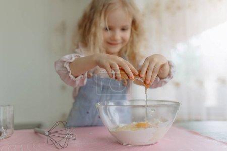 Photo for Cute girl selective focus, preparing food, broke a fresh egg into a transparent bowl. - Royalty Free Image