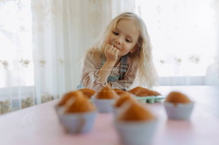 Foto de Niña se siente hambrienta, mirando dulces, cupcakes, pasteles - Imagen libre de derechos