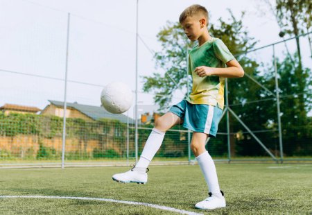 Téléchargez les photos : Le garçon joue avec le ballon sur le terrain de football - en image libre de droit