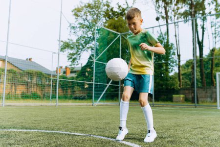 Foto de El niño juega con la pelota en el campo de fútbol - Imagen libre de derechos