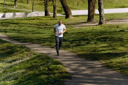 Photo for Bald man runs in the park. morning run. running in nature - Royalty Free Image