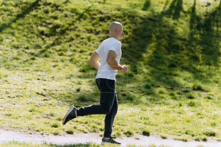 Photo for Bald man runs in the park. morning run. running in nature - Royalty Free Image