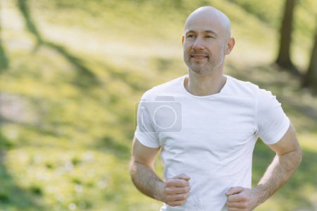Photo for Young man running in park with headphones on sunny summer day - Royalty Free Image